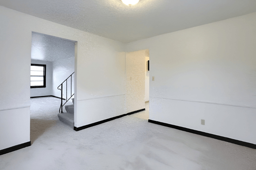 A white room with a staircase and a door.